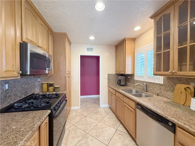 a kitchen with stainless steel appliances granite countertop a stove a sink and a microwave