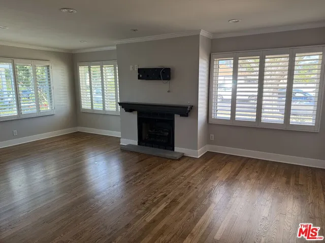 an empty room with wooden floor fireplace and windows