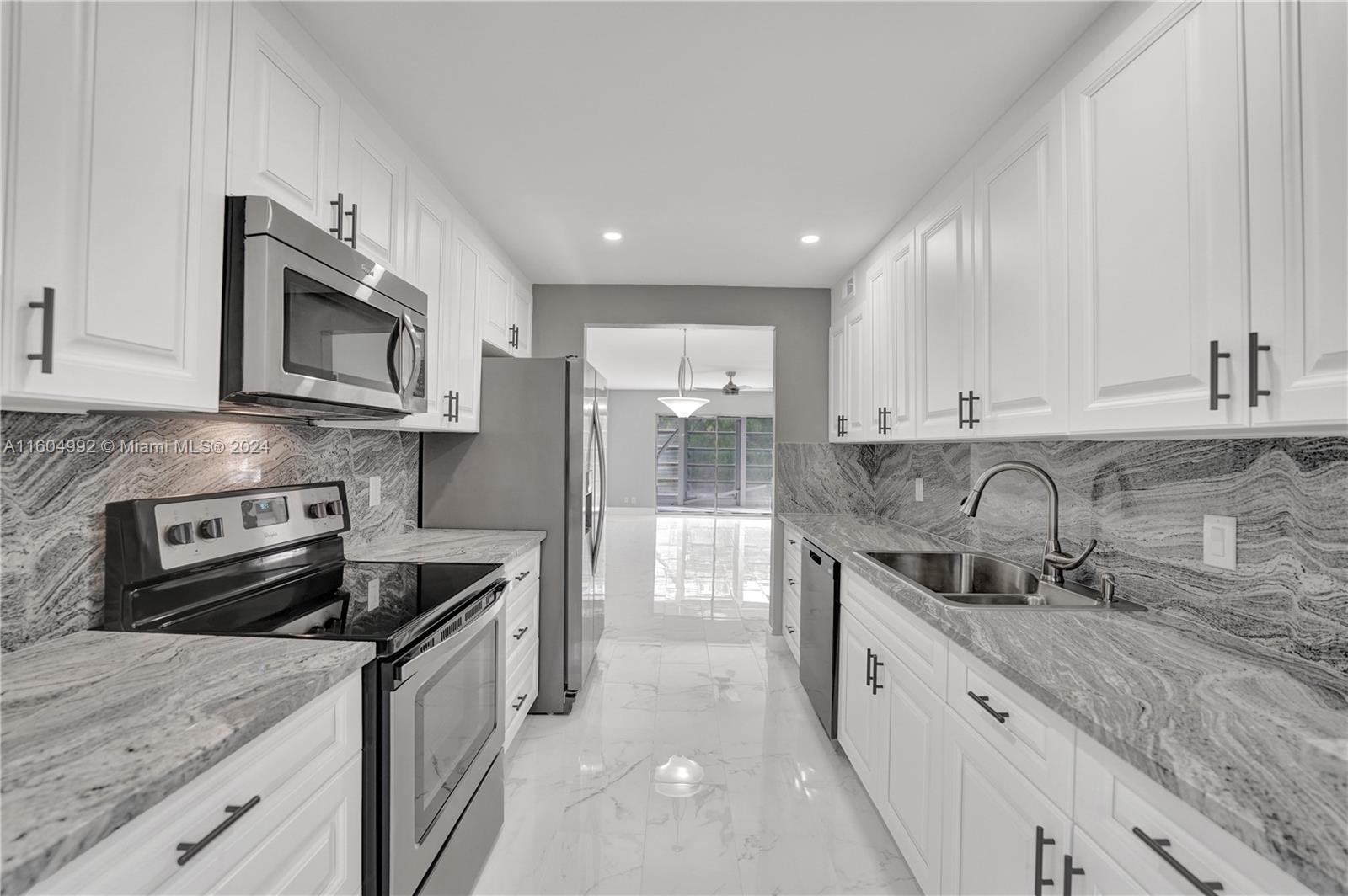 1802 Eleuthera Point, Unit E3 Coconut Creek, FL 33066 - Photo 13 of 78 a kitchen with stainless steel appliances granite countertop a sink stove microwave and cabinets