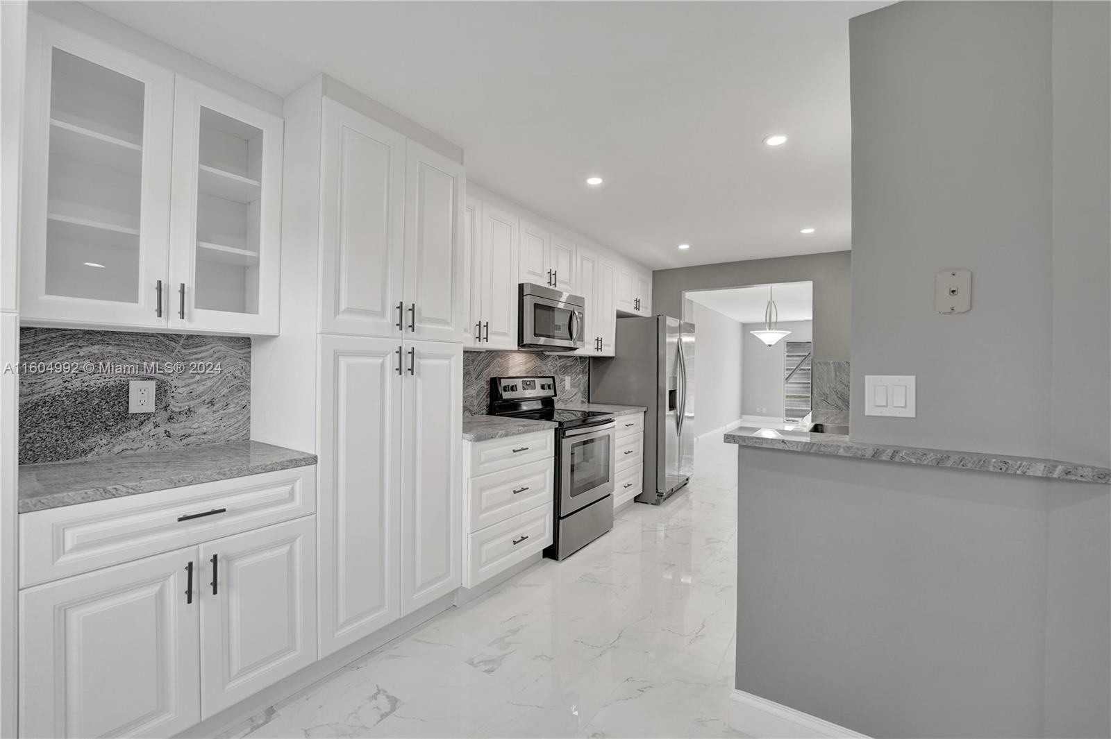 1802 Eleuthera Point, Unit E3 Coconut Creek, FL 33066 - Photo 4 of 78 a kitchen with granite countertop white cabinets and stainless steel appliances