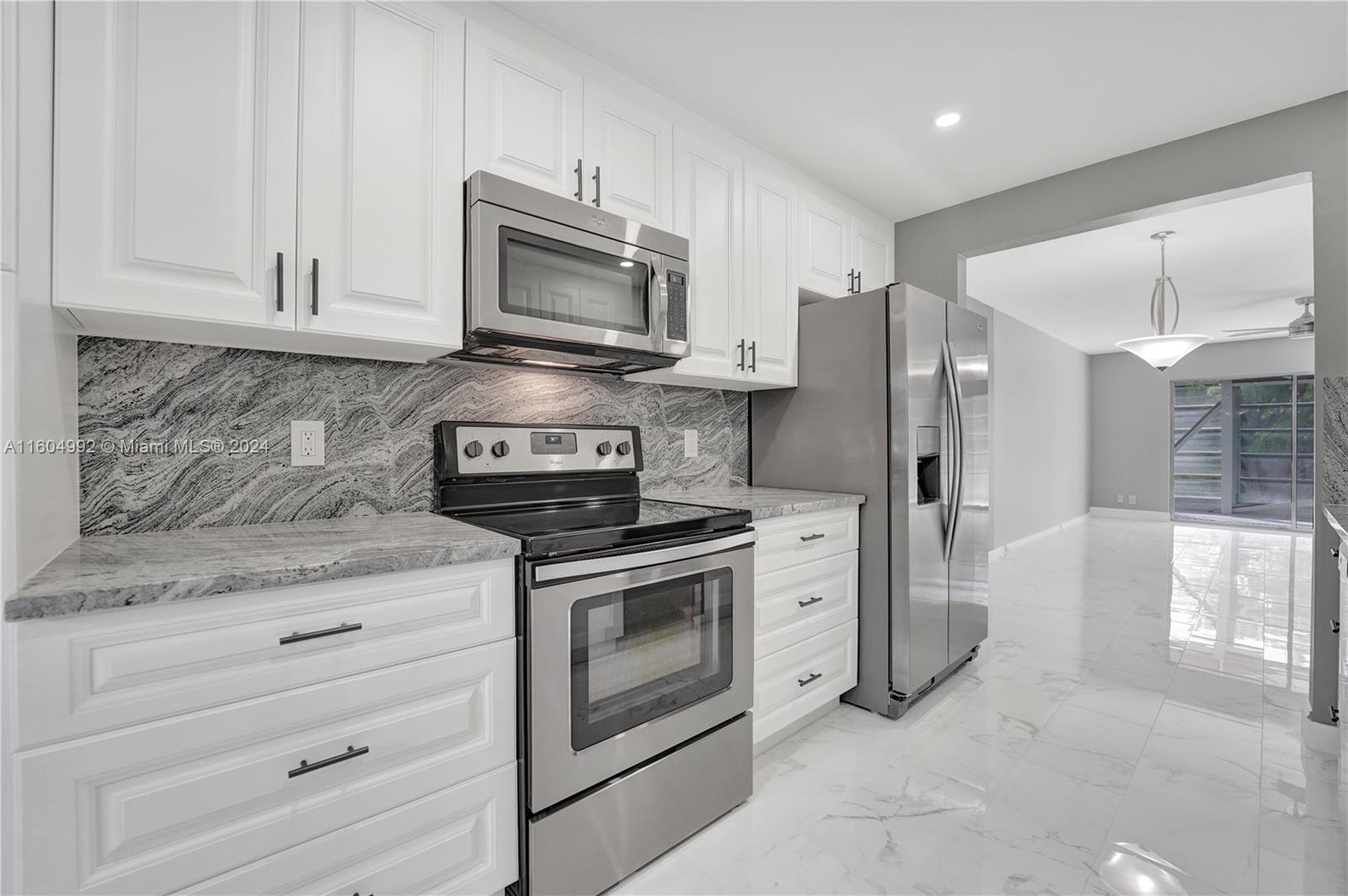 1802 Eleuthera Point, Unit E3 Coconut Creek, FL 33066 - Photo 5 of 78 a kitchen with white cabinets and stainless steel appliances