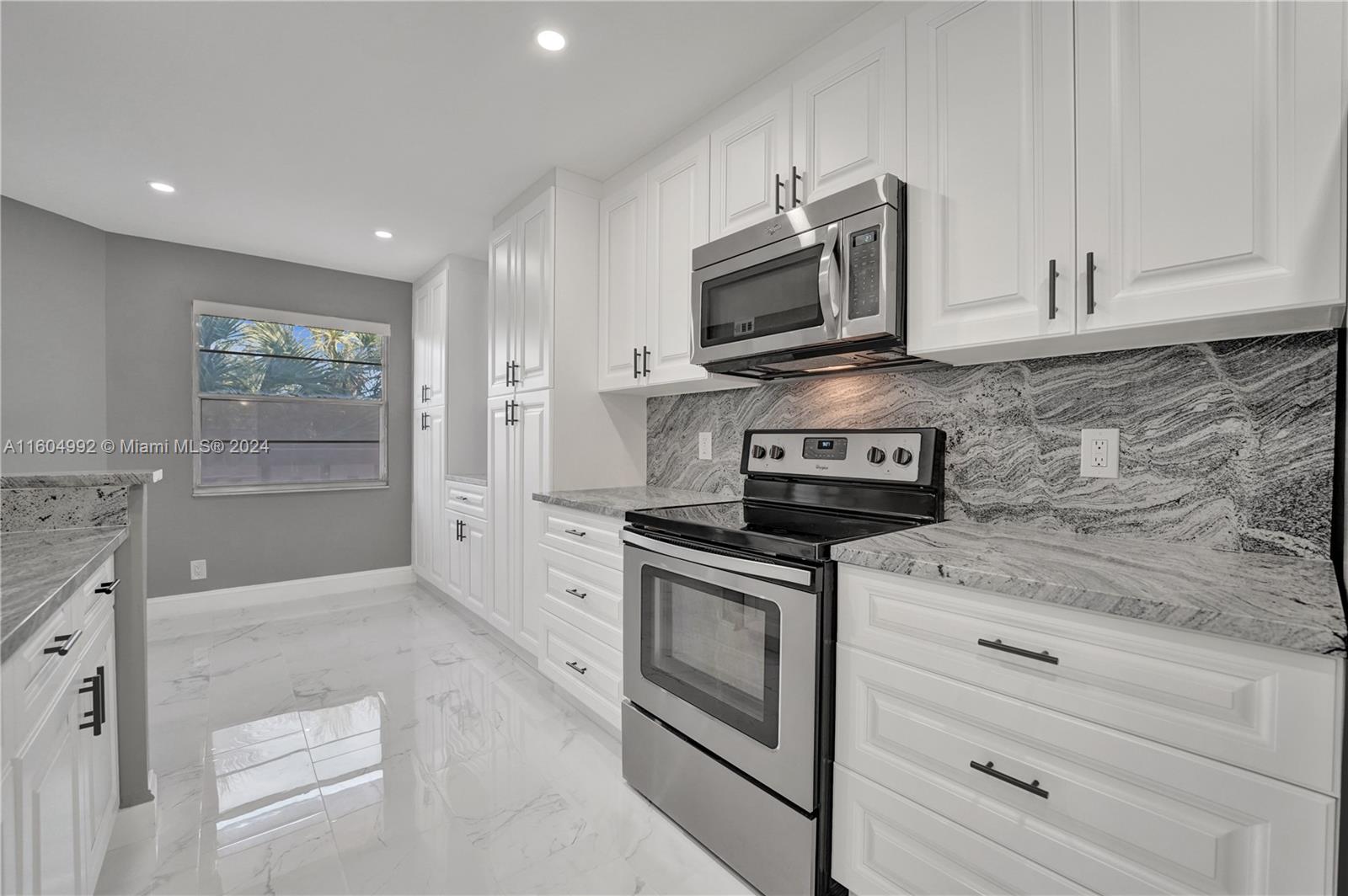 1802 Eleuthera Point, Unit E3 Coconut Creek, FL 33066 - Photo 6 of 78 a kitchen with stainless steel appliances granite countertop white cabinets granite counter tops and a stove