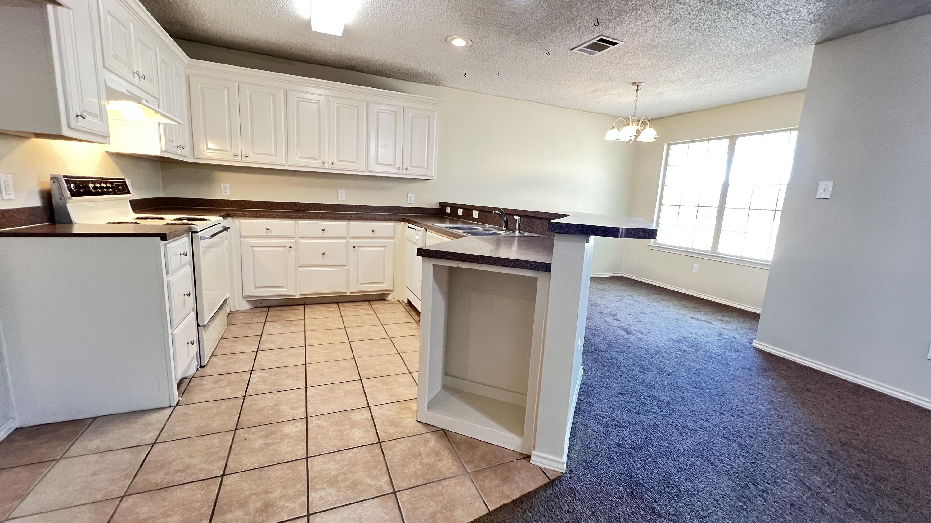 3102 110th Street Lubbock, TX 79423 - Photo 6 of 11 a kitchen with a sink a stove cabinets and counter space