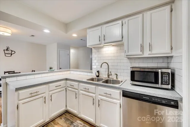 a kitchen with stainless steel appliances granite countertop a sink a stove and white cabinets