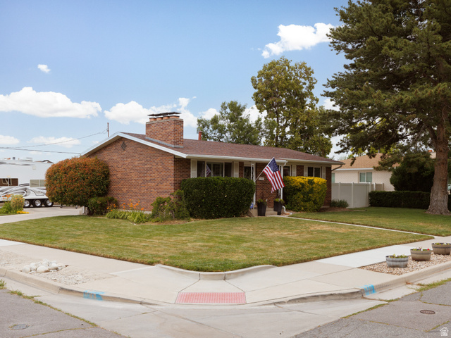 8252 Wood Street Midvale, UT 84047 - Photo 35 of 40 Brick exterior home featuring a prominent chimney, a covered front entry, and mature landscaping