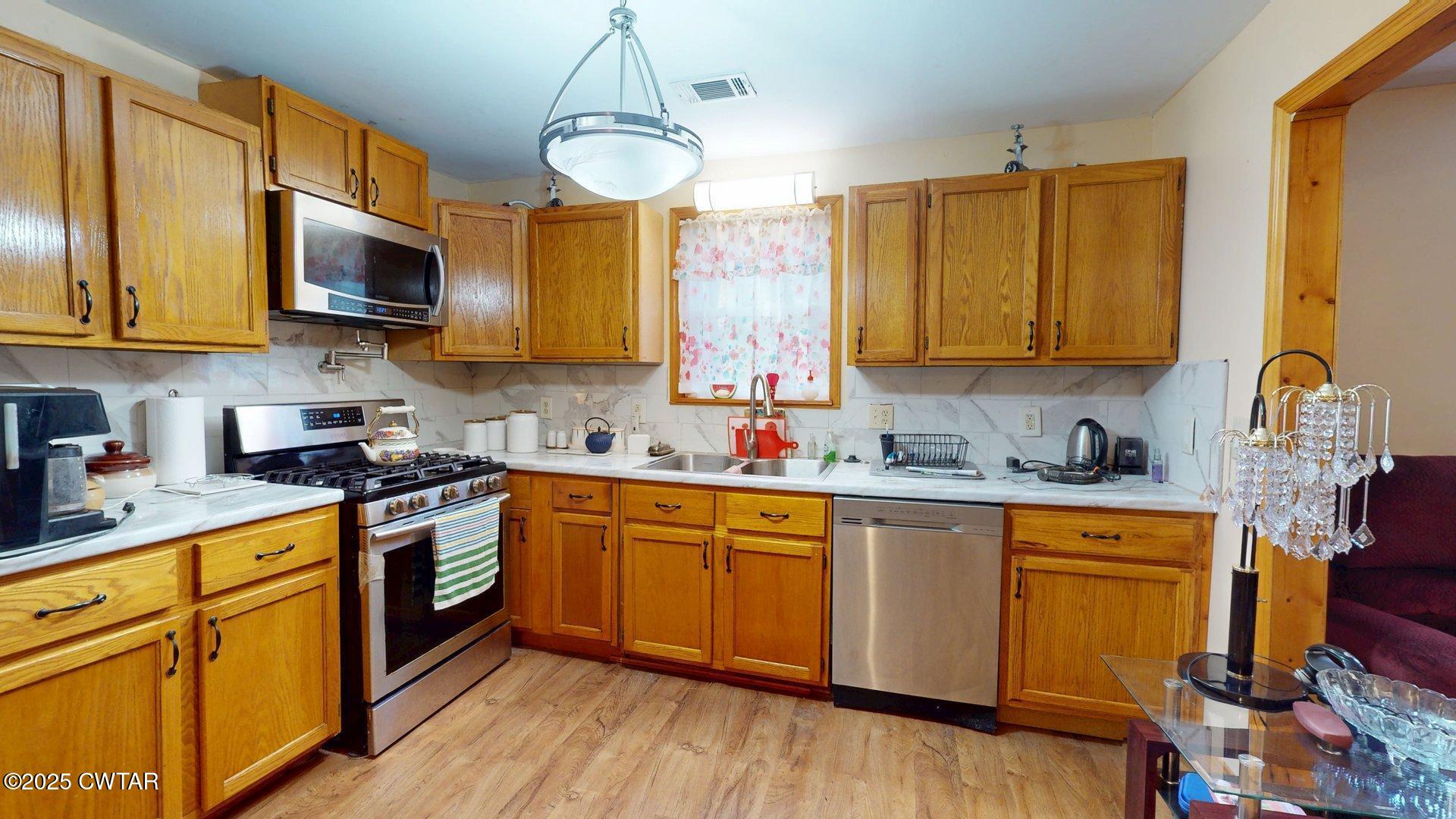 310 North Grayson Street Newbern, TN 38059 - Photo 2 of 22 a kitchen with stainless steel appliances granite countertop wooden cabinets a sink a stove a dining table and chairs with wooden floor