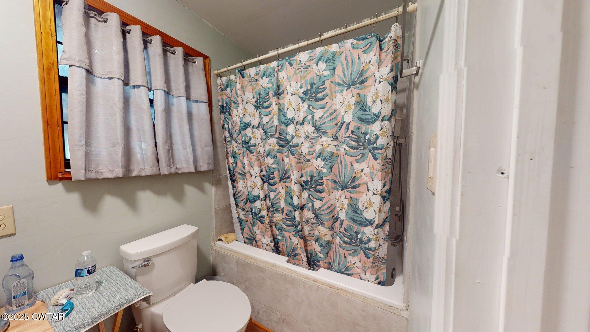 310 North Grayson Street Newbern, TN 38059 - Photo 10 of 22 a white toilet sitting next to a shower curtain