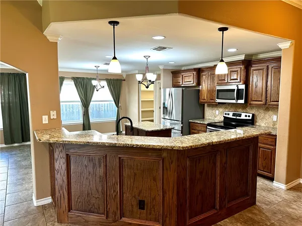 a kitchen with a stove a sink chandelier and living room view