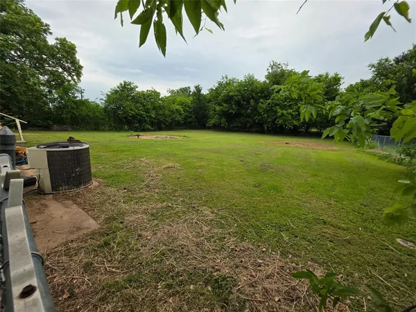 a view of a big yard with lawn chairs and large trees