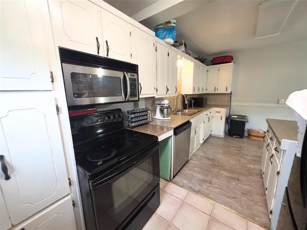 a kitchen with stainless steel appliances granite countertop a sink a stove a microwave a counter space and cabinets