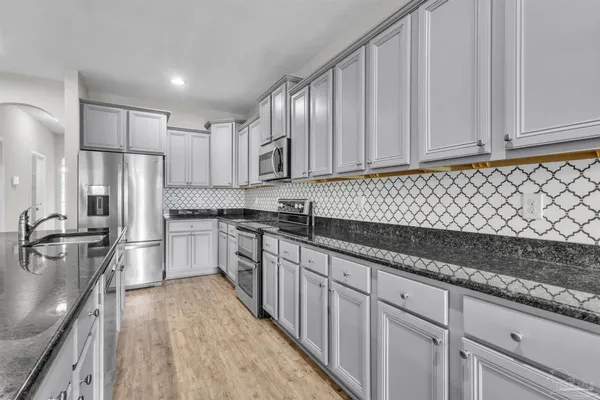a kitchen with granite countertop a sink stainless steel appliances and cabinets