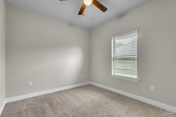 an empty room with a window and a ceiling fan