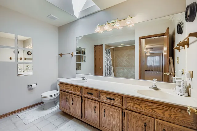a bathroom with a granite countertop double vanity sink mirror and toilet