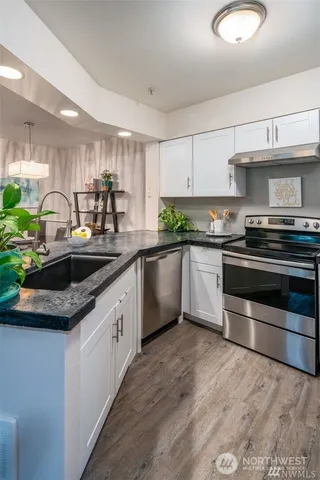 a kitchen with stainless steel appliances granite countertop a sink a stove and cabinets