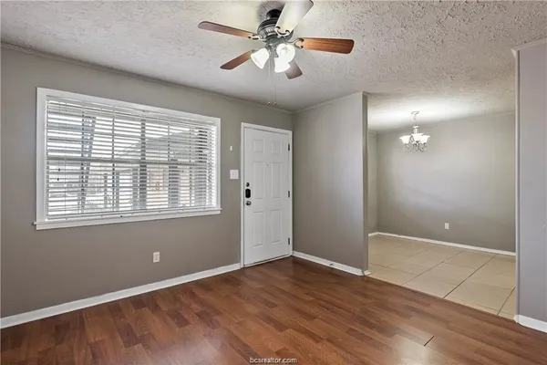 a view of an empty room with window and wooden floor