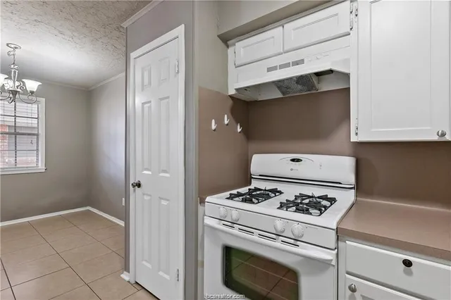 a kitchen with a stove and white cabinets