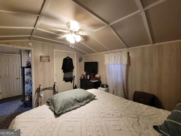 a bedroom with a bed large mirror and a flat tv screen