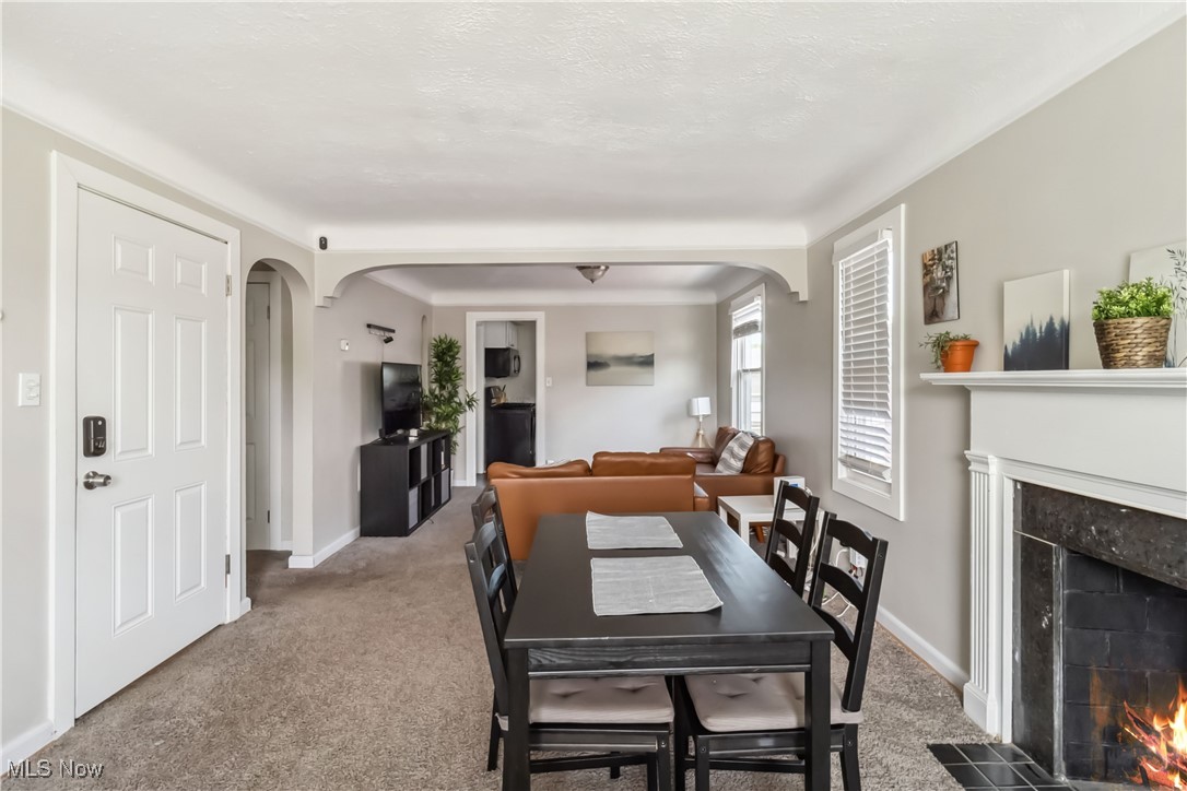 13641 Cedar Road Cleveland, OH 44118 - Photo 13 of 42 Carpeted dining area with a fireplace, arched walkways, and baseboards