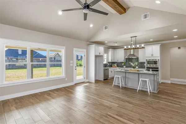 a open kitchen with stainless steel appliances granite countertop a refrigerator a stove top oven a dining table and chairs with wooden floor