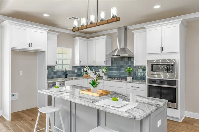 a kitchen with stainless steel appliances granite countertop a stove top oven a sink a stove and white cabinets