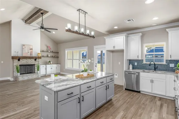 a kitchen with kitchen island granite countertop a sink cabinets and wooden floor