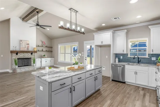 a kitchen with kitchen island granite countertop a sink cabinets and wooden floor