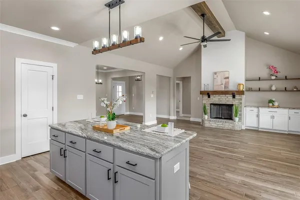 a hallway with kitchen island a chandelier and wooden floor