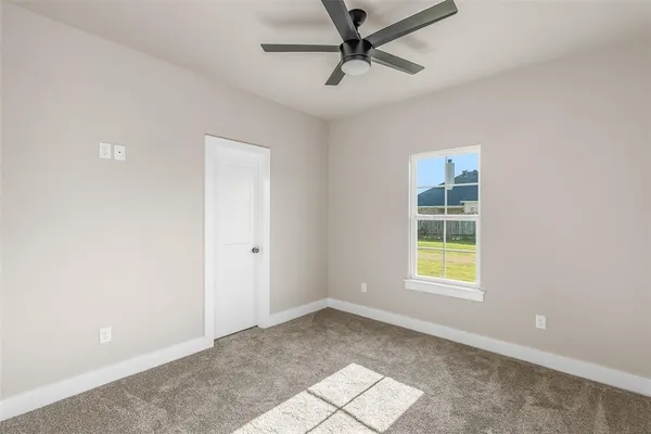 an empty room with a window and ceiling fan