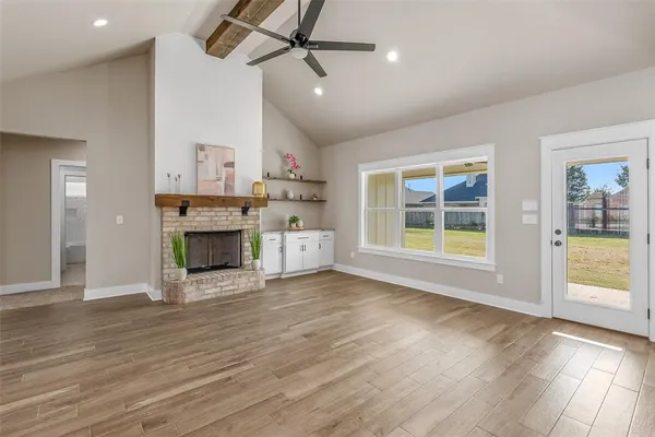 an empty room with wooden floor a fireplace and windows