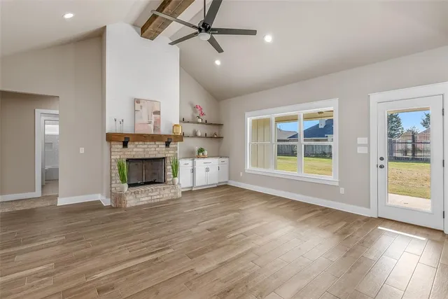 an empty room with wooden floor a fireplace and windows