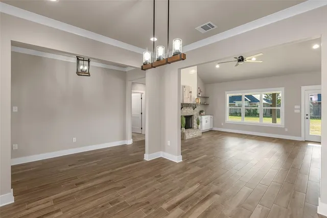 a view of an empty room with a window and wooden floor