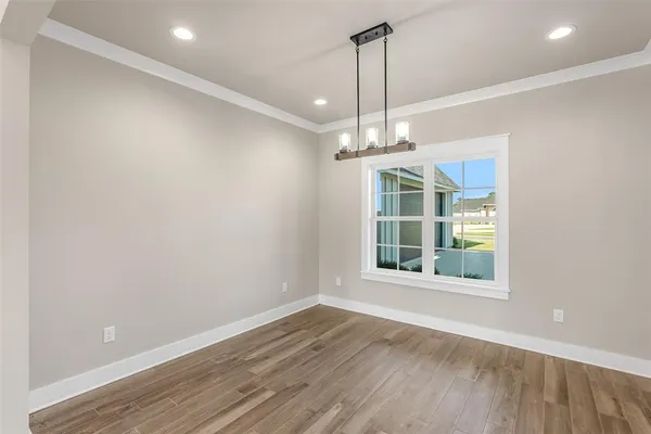 a view of an empty room with wooden floor exposed radiator and a large window