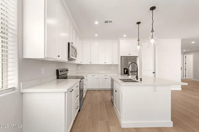 a kitchen with kitchen island white cabinets stainless steel appliances and a chandelier