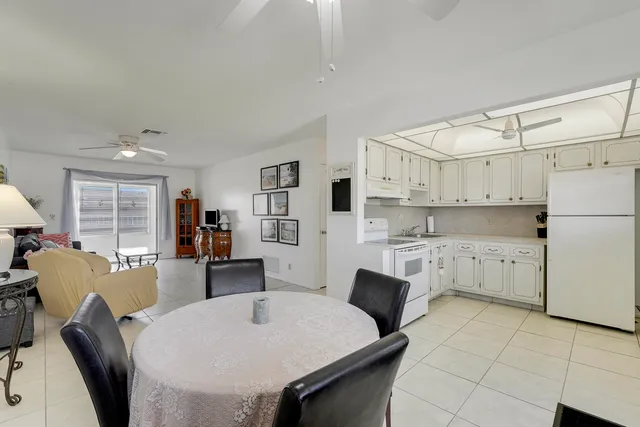 a kitchen with stainless steel appliances a stove a refrigerator a sink a dining table and chairs