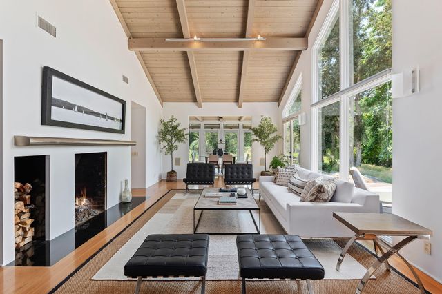 a living room with furniture fireplace and large windows