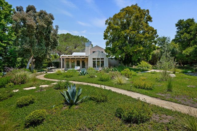 a view of a house with a big yard plants and large trees