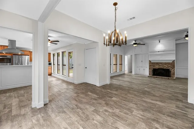 a view of a livingroom with a fireplace a chandelier and wooden floor