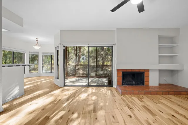 a view of empty room with floor to ceiling window and kitchen view