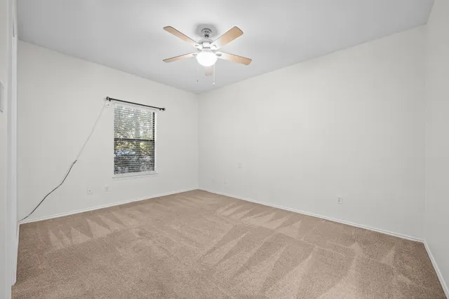 an empty room with windows and ceiling fan