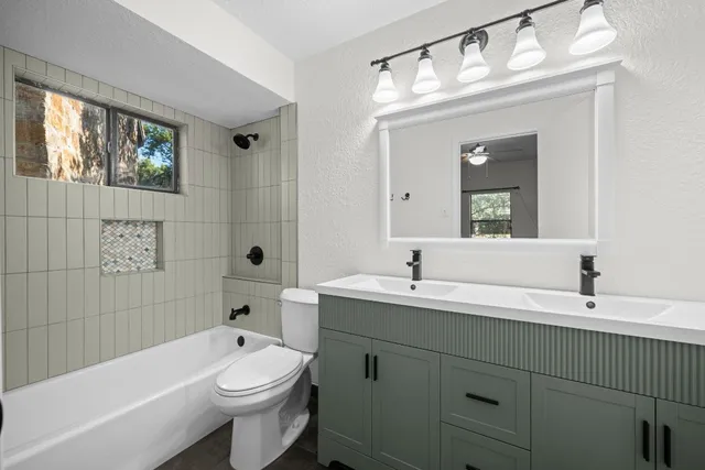 a bathroom with a toilet a sink a mirror a bathtub and vanity