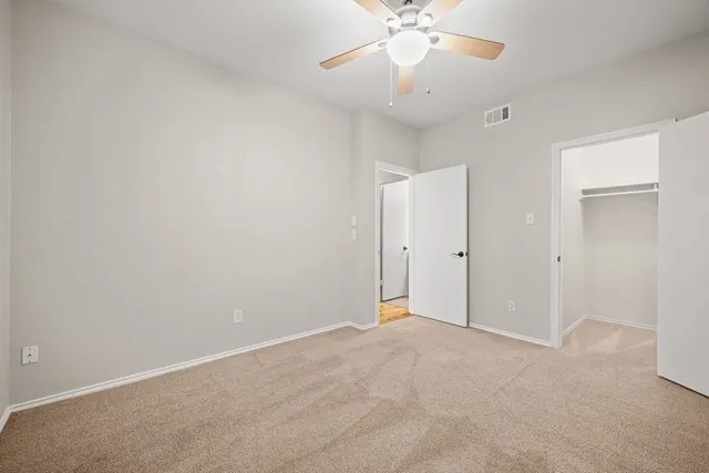 an empty room with a chandelier fan and a ceiling fan