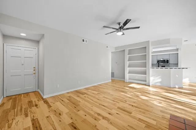 a view of a livingroom with wooden floor and a ceiling fan