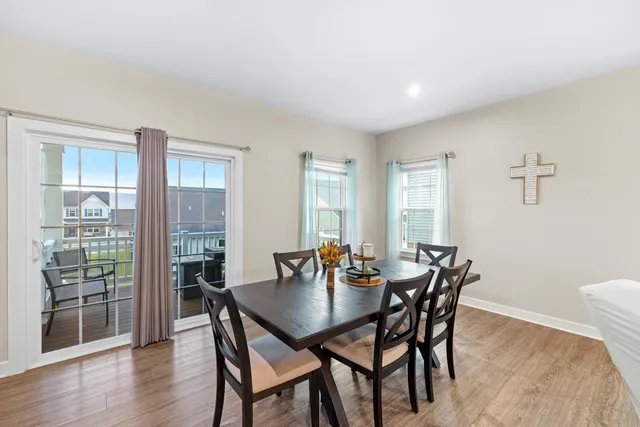 a kitchen with stainless steel appliances kitchen island granite countertop a refrigerator a stove a sink a dining table and chairs with wooden floor