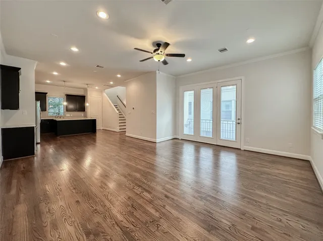 a view of an empty room with wooden floor and a ceiling fan