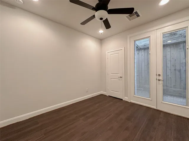 an empty room with wooden floor and ceiling fan