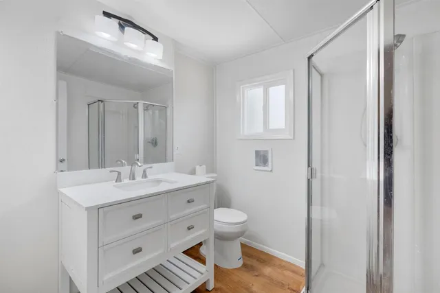 a bathroom with a toilet a sink a mirror a window and vanity