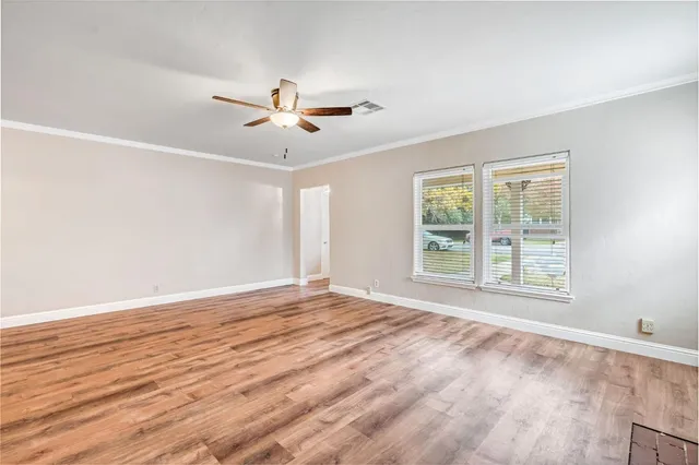 a view of an empty room with a window and wooden floor