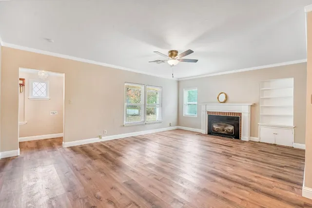 an empty room with windows fireplace and wooden floor