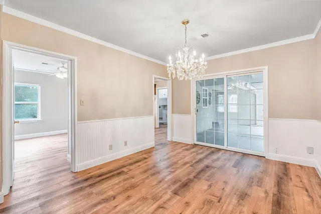 a view of an empty room with wooden floor and a chandelier