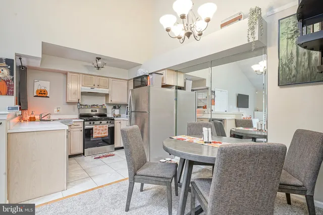 a kitchen with a refrigerator a stove a sink dishwasher a dining table and chairs with wooden floor